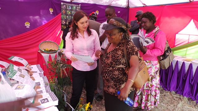 Dr Parveen Anjarwalla from the World Agroforestry Centre (ICRAF) holding a leaflet about pesticidal plants and explaining how to use for crop protection to one of many farmers attending the Machakos Agricultural show